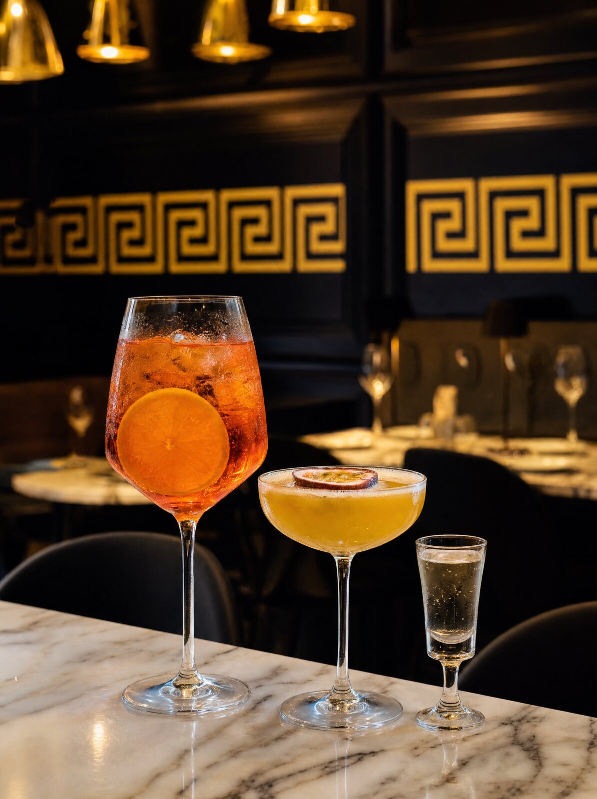 Two handcrafted cocktails on the bar at Dine & Dessert Kirkham, garnished with orange